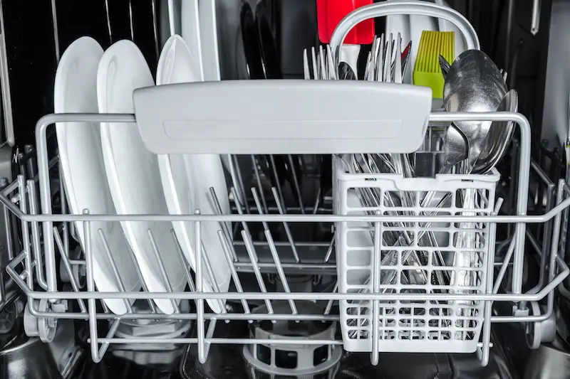 White dishes loaded in dishwasher lower rack 